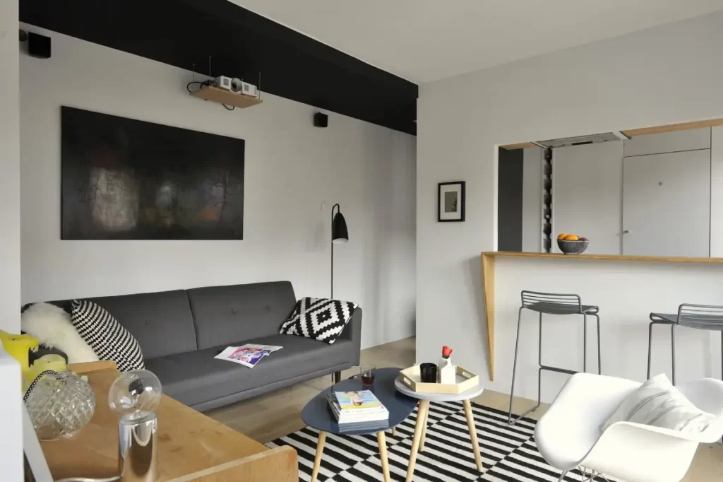 salon avec un canapé gris, une télé accroché sur le mur et une petite table basse