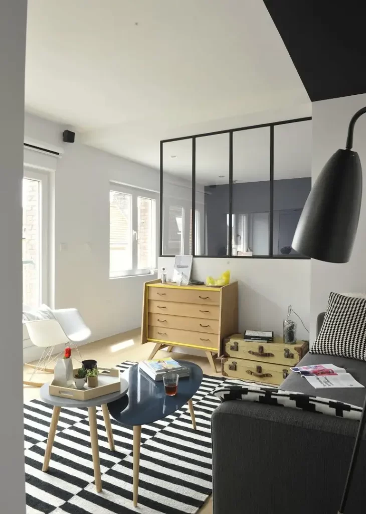 aménagement d'un appartement avec une table basse des objets avec une verrière dans le fond