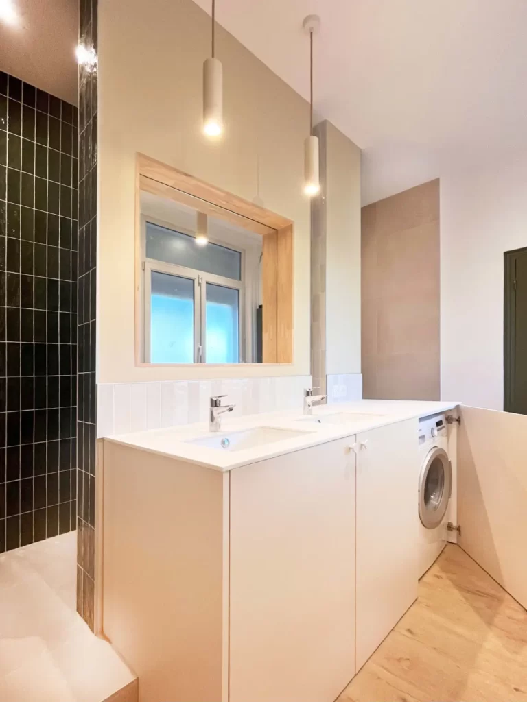 salle de bain blanche éclairée avec une machine à laver et un robinet