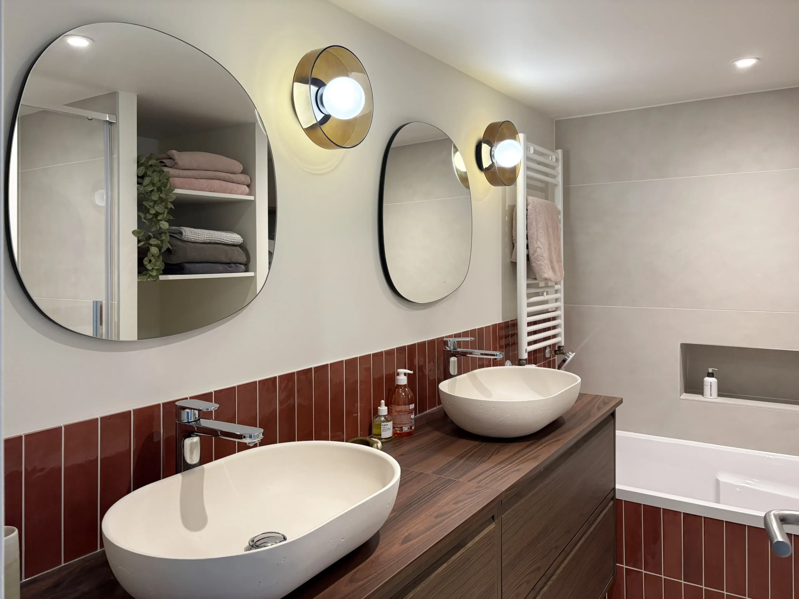 Salle de bain compacte qui comporte une douche à l'italienne, une double vasque déco, une baignoire confortable. Des meubles IKEA s'intègrent parfaitement, permettant de respecter le budget travaux